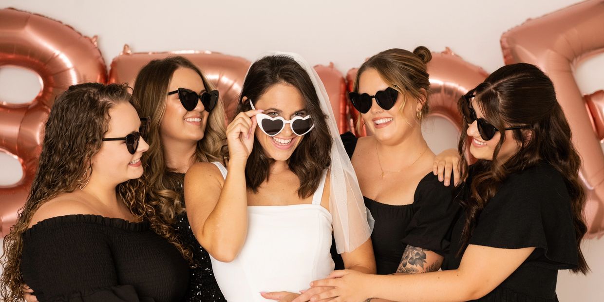 Bridesmaids with sunglasses on hugging the bride with white sunglasses, destin bachelorette party 