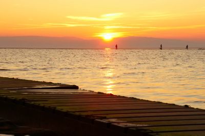 Sunset over a lake with a dock in the foreground.