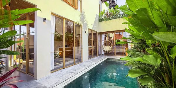Modern house with glass doors opening to a lush pool area.