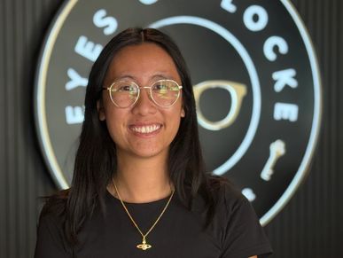 Smiling woman wearing glasses and a black shirt indoors.