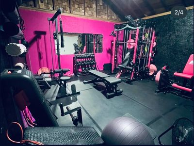 Home gym with various workout equipment and pink walls.