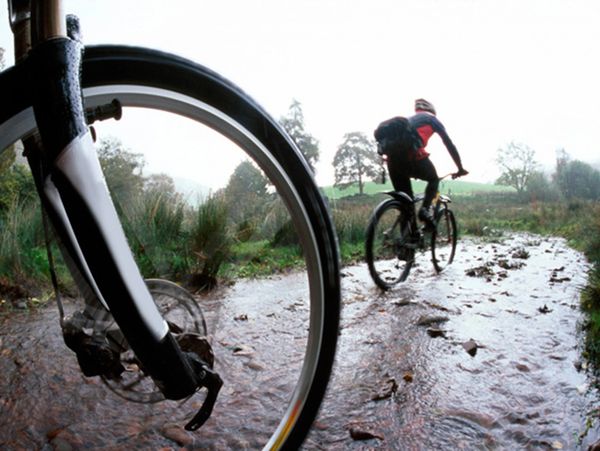 Two men riding bikes on water.