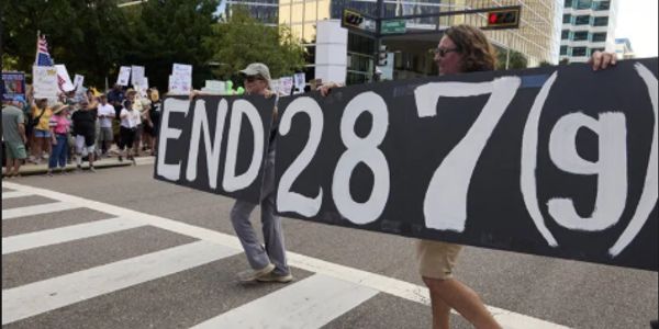 Protesters holding a large sign that says 'END 287(g)'.