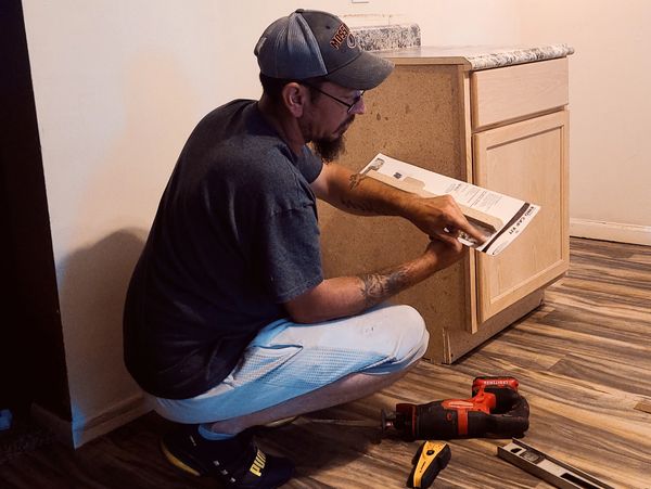 Man reading instructions while assembling a kitchen cabinet.