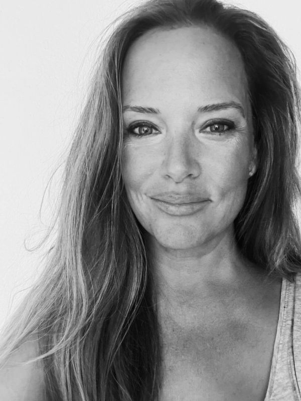 Black and white close-up portrait of a woman with long hair and a serene smile.