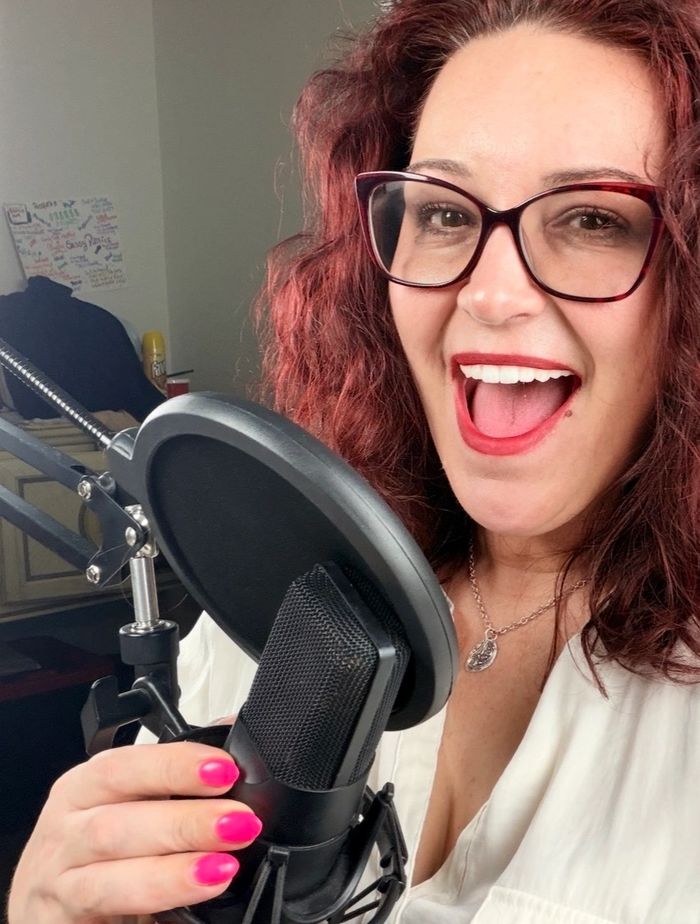 Christi Chanelle smiling at her podcast microphone.