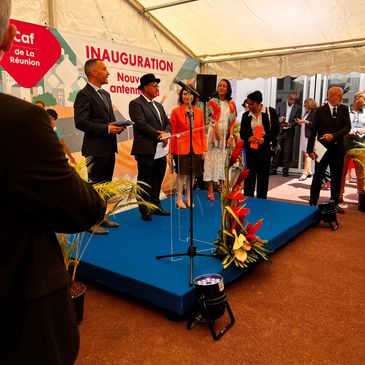 People dressed formally at a ribbon-cutting inauguration event under a tent.