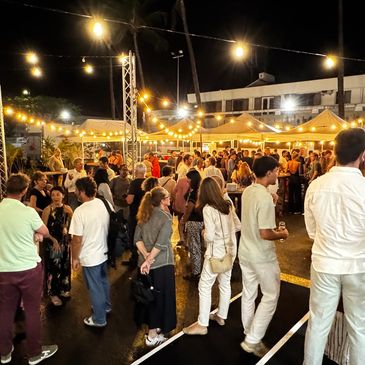 Nighttime outdoor party with string lights and people socializing.