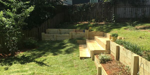 A wooden retaining wall with steps and garden beds built in at multiple levels. 