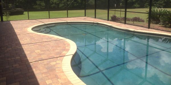 A clean, re-paved beige deck around an existing pool.