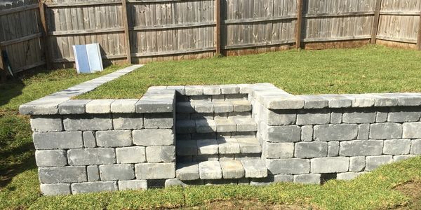 A grey stone retaining wall with steps and drainage built in.