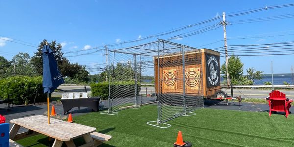 Outdoor recreational area with axe throwing targets and picnic seating.
