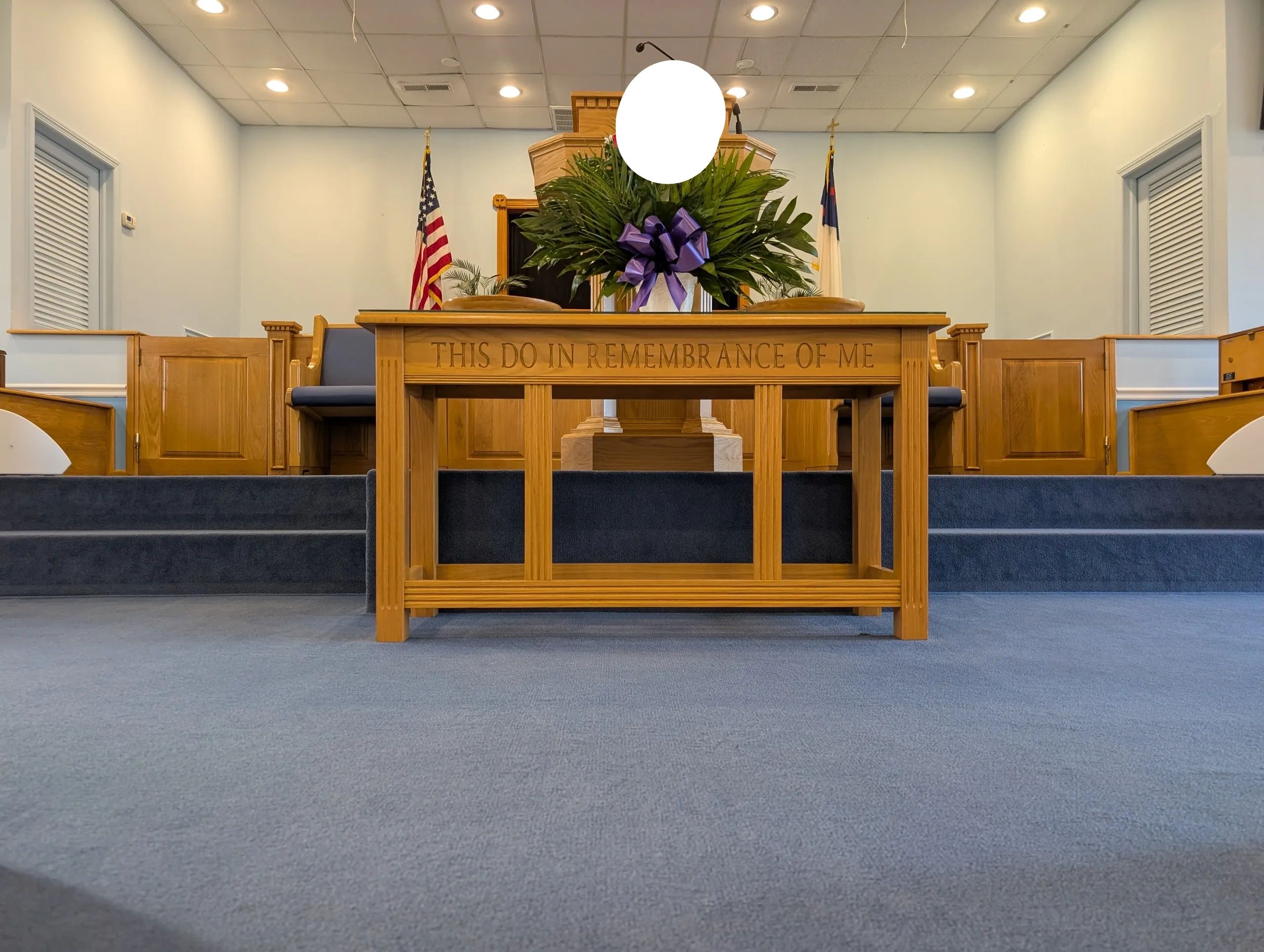 Church altar with floral arrangement and patriotic flags.