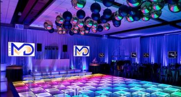 Colorful LED-lit dance floor in a modern event space with disco balls.