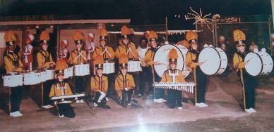 Marching band in yellow uniforms posed with instruments.