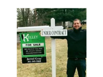 Man stands next to a real estate sign marked 'Under Contract'.
