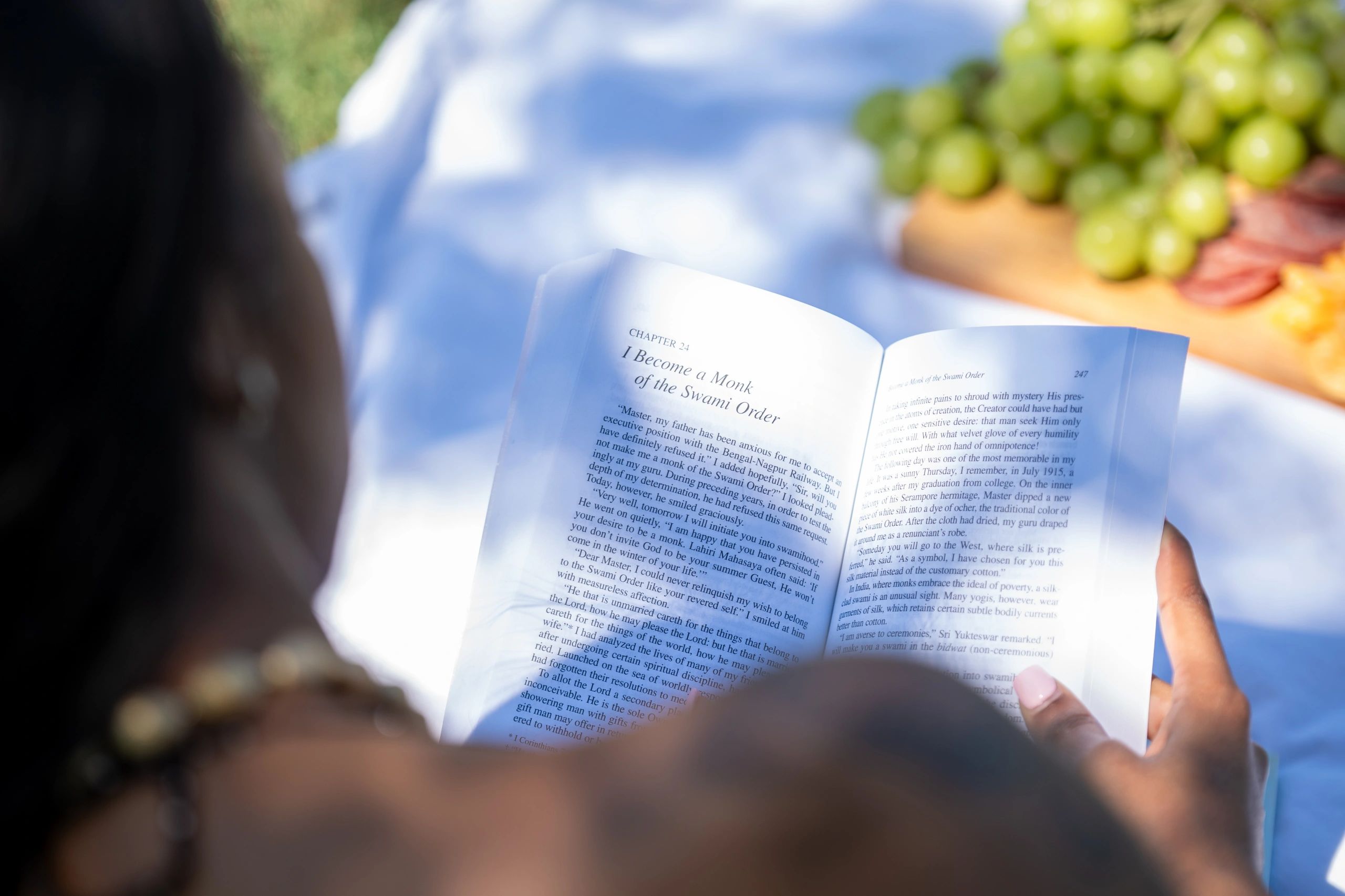 Person reading a book titled 'I Become a Monk of the Swami Order' outdoors.