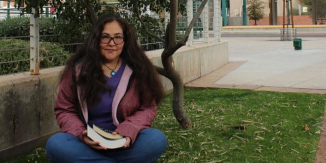 Woman sitting on grass with a book.