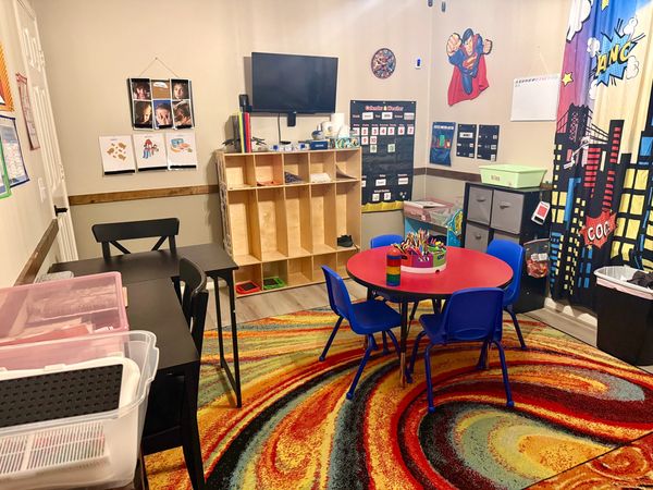 Colorful and organized classroom with a round table and superhero-themed decor.
