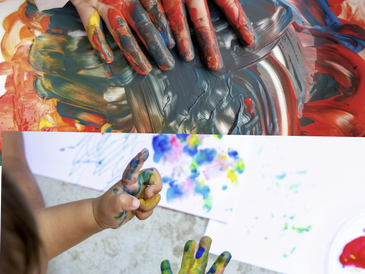 Children's hands covered in colorful paint, creating vibrant artwork.