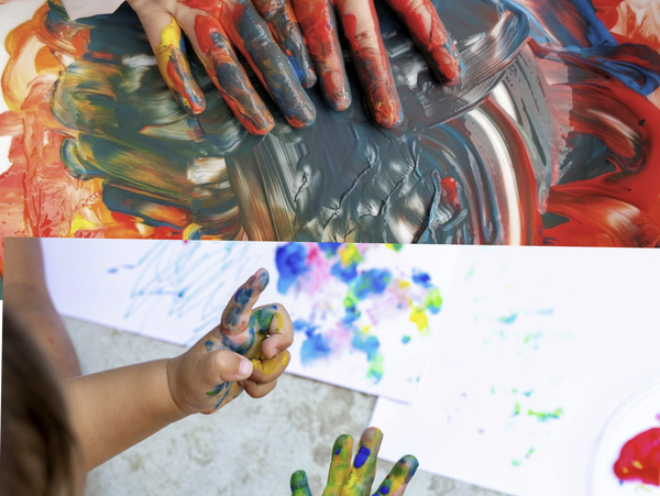 Children's hands covered in colorful paint, creating vibrant artwork.