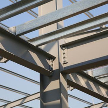 Close-up of steel beams forming a structural framework under clear sky.