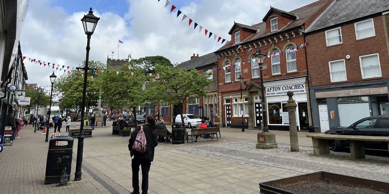 A lively town square with people and festive bunting.