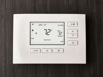 Digital thermostat displaying 72°F on a dark wall.