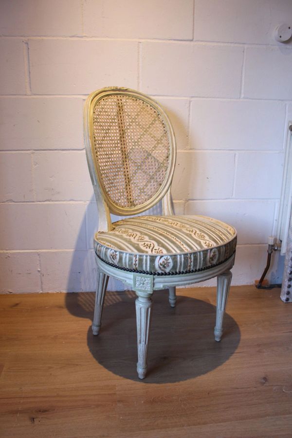 Vintage upholstered chair with a woven backrest on a wooden floor.