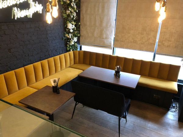 Cozy corner seating with mustard yellow cushions and warm lighting in a café.