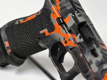 Close-up of an orange and black camo-patterned gun trigger area.
