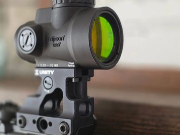 Close-up of a Trijicon scope mounted on a rifle.