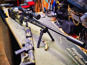 Two rifles on a workbench with tools in the background.