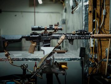 A tactical rifle with a scope mounted indoors.