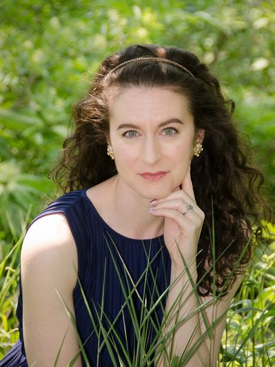 A picture of writer Elizabeth Niarchos Neukirch in a park surrounded by greenery.
