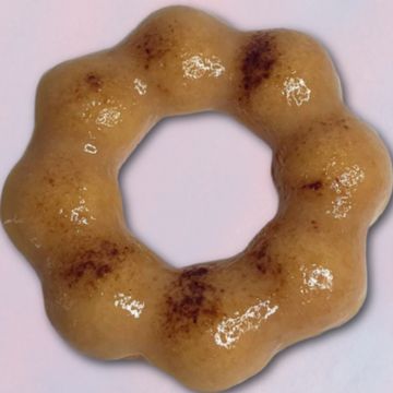 A glossy, ring-shaped pastry with a bumpy texture and brown spots.