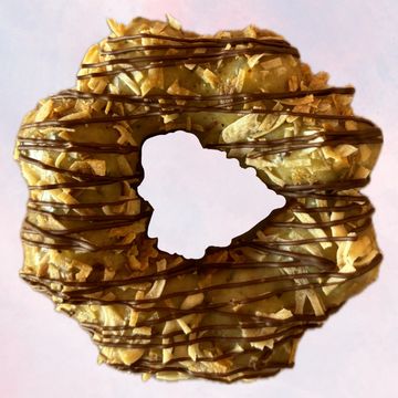 A donut with nuts and chocolate drizzle shaped like Hawaii.