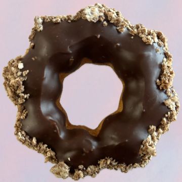 Chocolate-glazed donut with granola topping on a pink background.