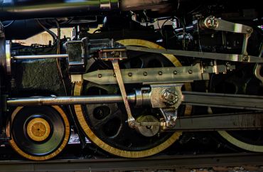 Close-up of a vintage steam locomotive's driving wheels and mechanical rods.