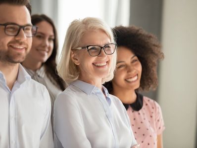 Side view of smiling diverse employees stand in row together posing for group picture