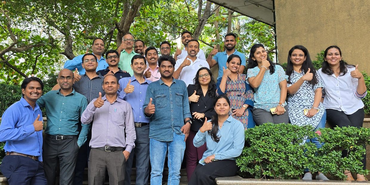 A diverse group of office colleagues giving thumbs up outdoors.