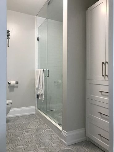 Custom Built-In Linen and Towel Closet for Bathroom with Shaker Panels in addition to a Custom Tempered Glass Enclosure.