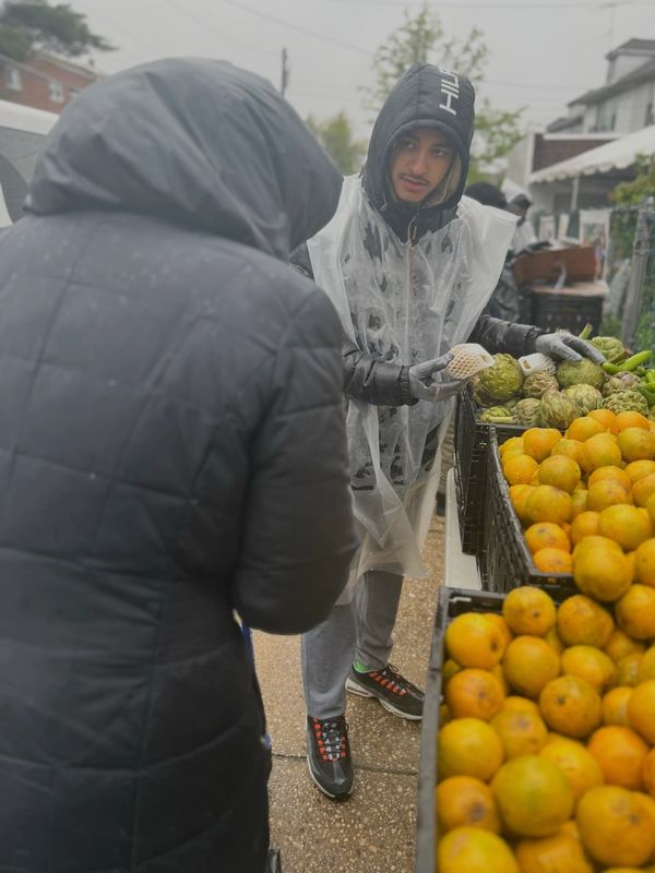 Man selling fruits outside in rainy weather.