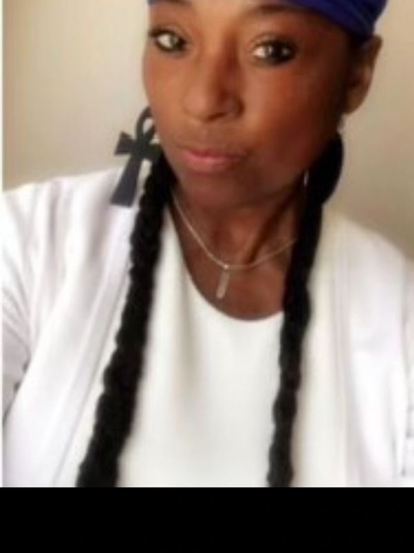 Woman with braids wearing a headscarf and ankh earrings.
