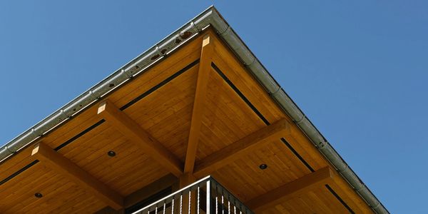 Wooden roof corner under a clear blue sky.
