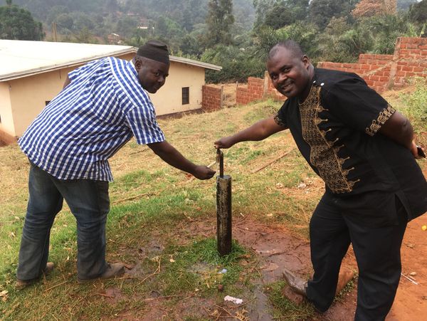 Eugene Lendzemo and School Master checking the water tap