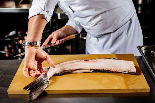 Chef preparing a fish on a cutting board.