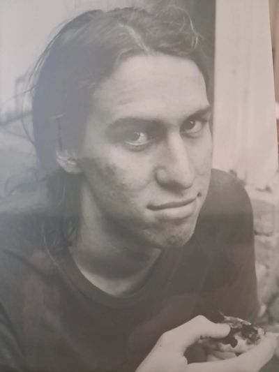 Black and white portrait of a young person with long hair holding food.