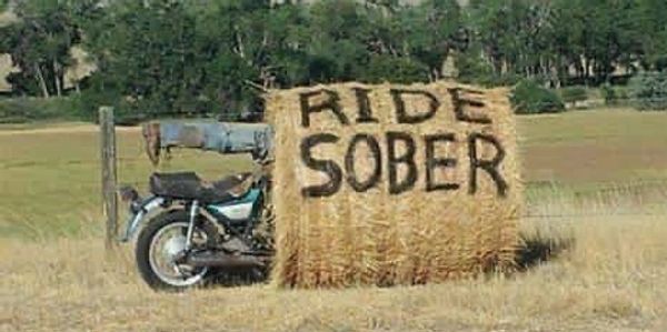 Motorcycle in a hay bale. In black letters on the hay bale it says: “RIDE SOBER”