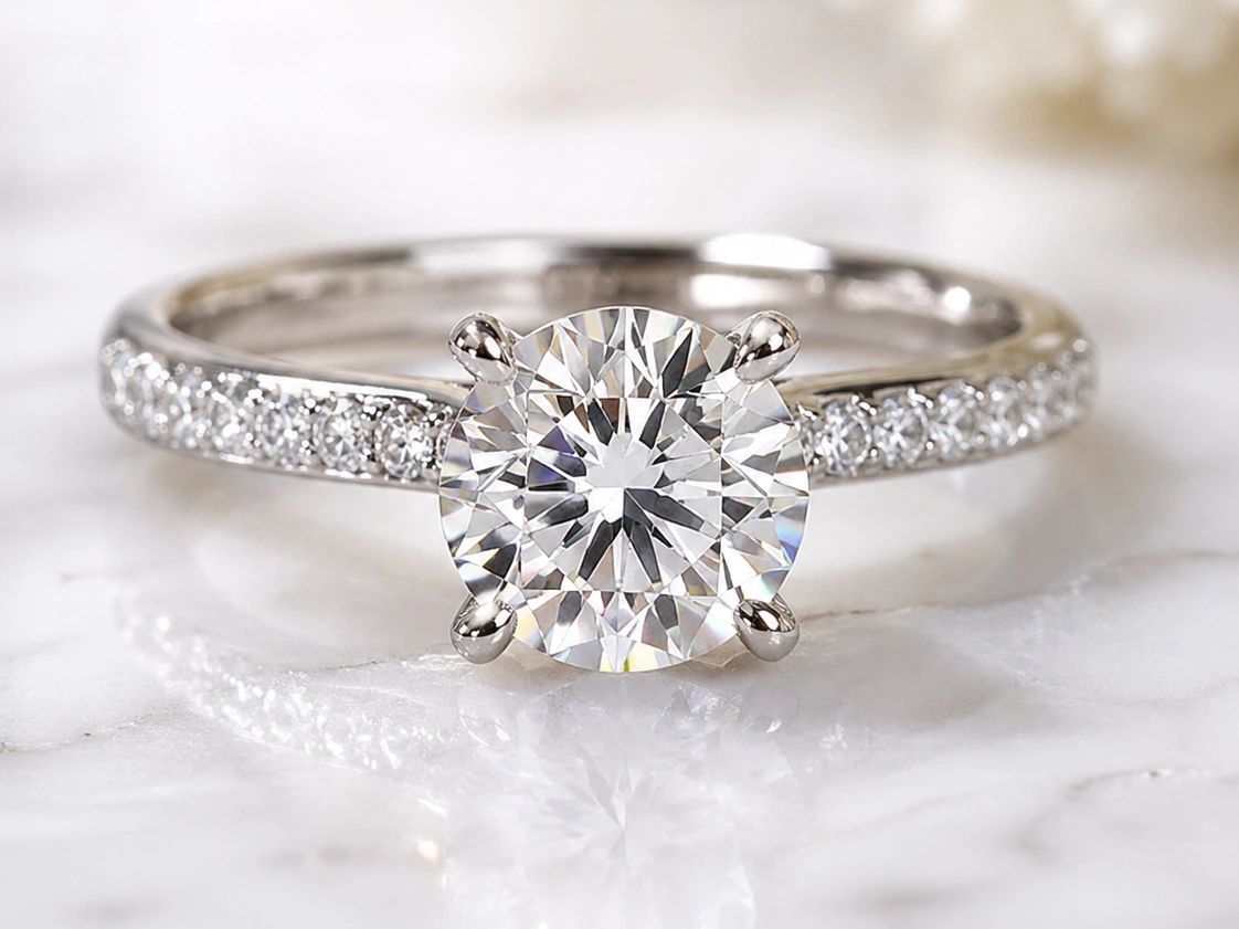 A stunning solitaire diamond ring resting on a smooth white marble surface.